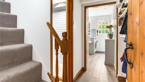 A staircase leading to a laundry area with a wooden handrail and a shoe rack on the right. - Little Braybrooke Cottage- Saffron Walden (Saffron Walden)