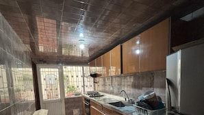 Una cocina con paredes de azulejos, un refrigerador de acero inoxidable, un lavamanos y una estufa.