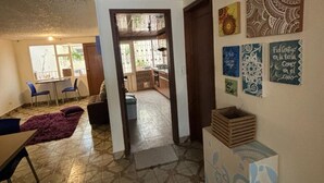 Un salón amplio con suelo de baldosas, una mesa de comedor con sillas y una cocina al fondo.