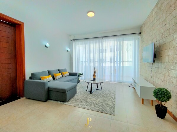 A modern living room with a grey sectional sofa, a small round table, and a potted plant.