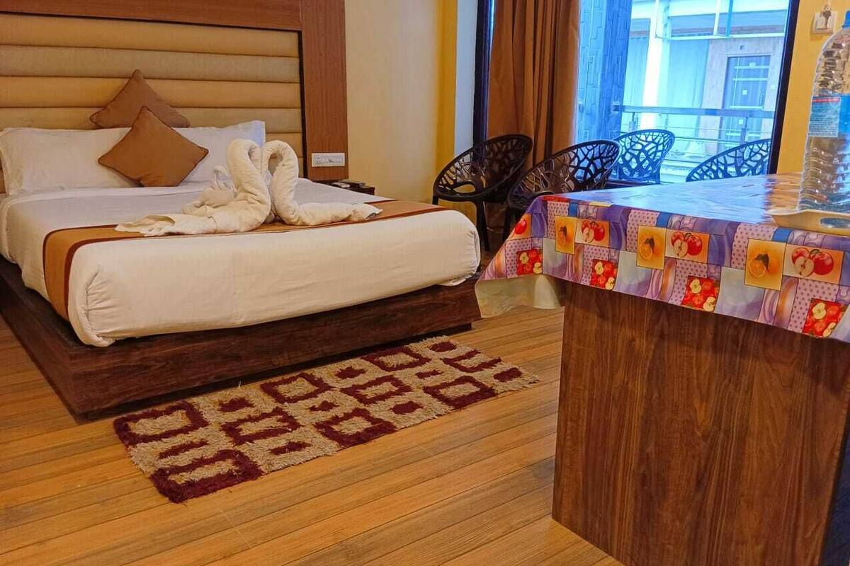 Een hotelkamer met een houten bed, een kamerbreed tapijt met een patroon en een tafel met een kleurrijke tafelkleed.