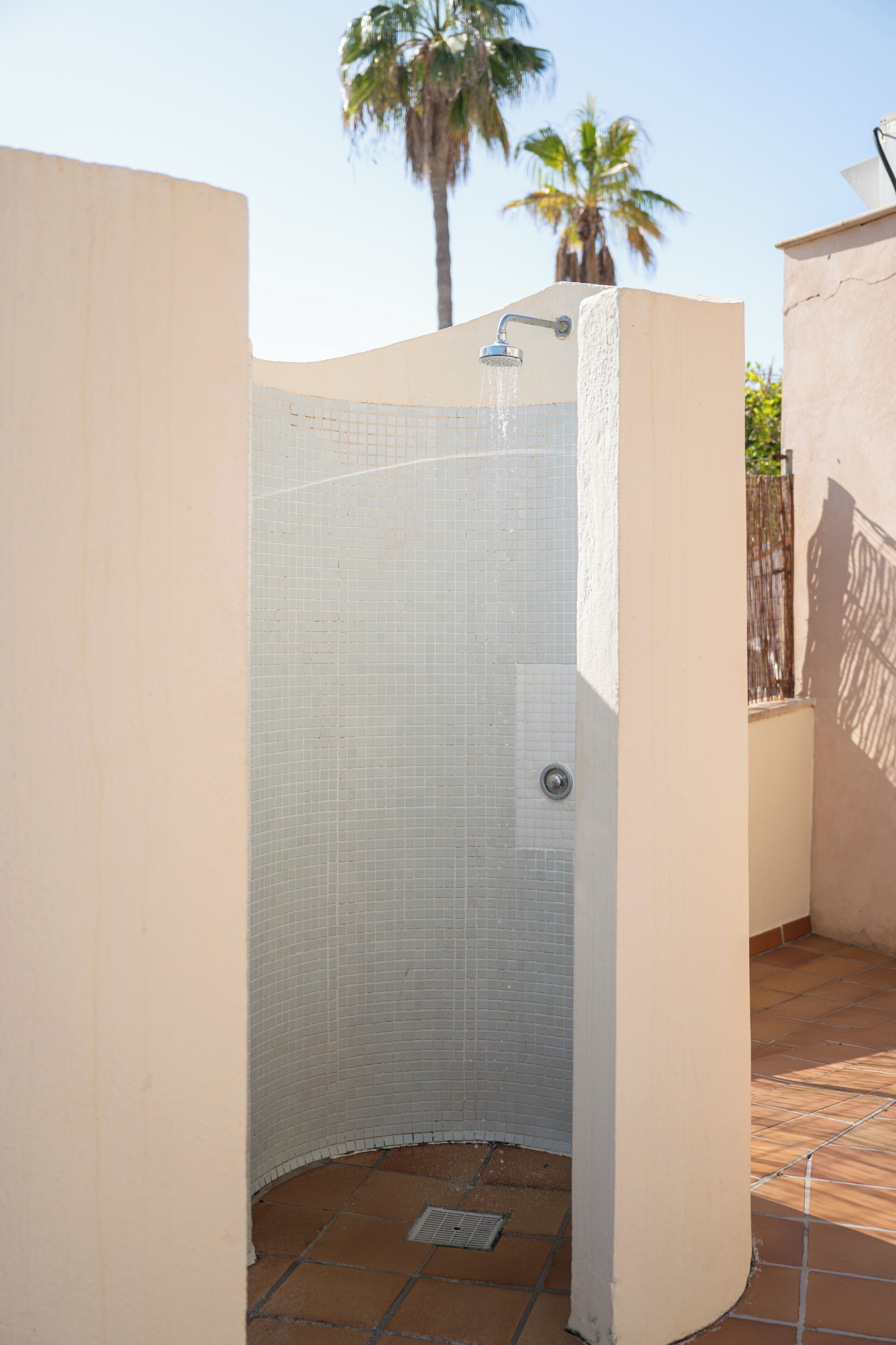 Un área de ducha pequeña y cerrada, con paredes de azulejos y un cabezal de ducha metálico.