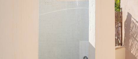 Un área de ducha pequeña y cerrada, con paredes de azulejos y un cabezal de ducha metálico.