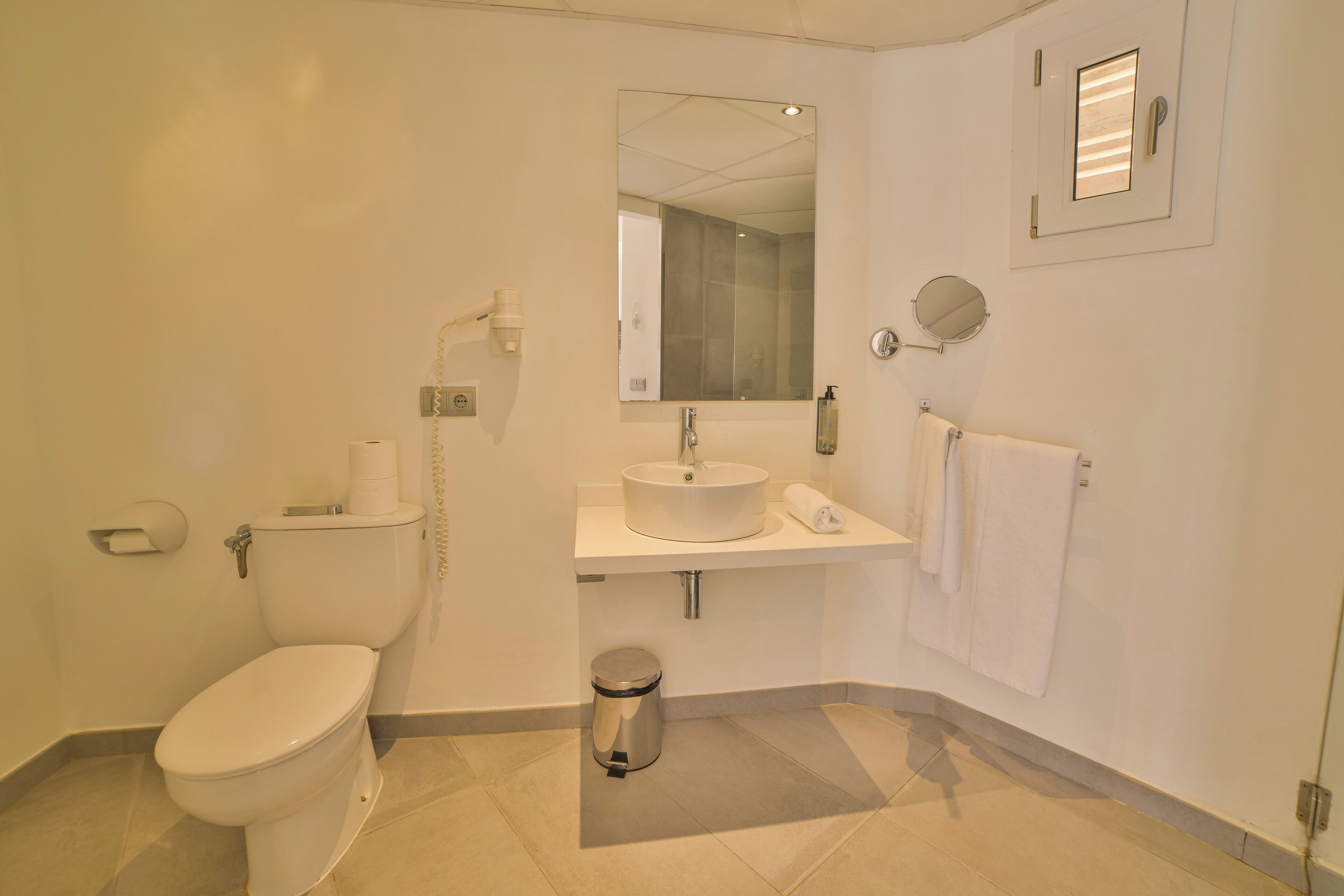 A modern bathroom with a toilet, sink, mirror, and towel rack.