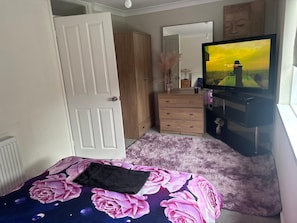 A bedroom with a bed, a dresser, a television, and a window.
