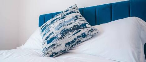 A bed with white bedding and a blue headboard.