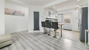 A modern kitchen with white cabinets, a black countertop, and three bar stools.