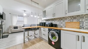 A modern kitchen with white cabinets, a wooden countertop, and a washing machine.