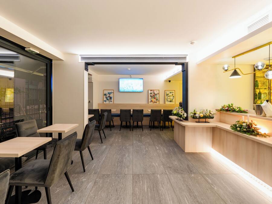 A modern hotel lobby with a reception desk, seating area, and a television screen.