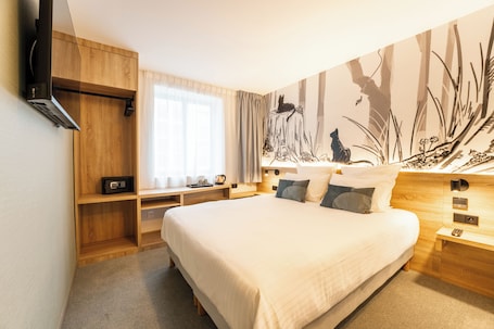 A modern bedroom with a large bed, wooden nightstands, a built-in TV, and a mural on the wall.