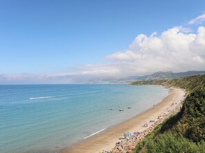 A coastal beach with clear waters, a sandy shore, and a rocky hillside. - Bryn Moelyn Cottage (Pwllheli)