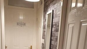 Un couloir avec une porte blanche portant l’inscription « SALLE DE BAINS » et une autre porte portant l’inscription « TOILETTES ».