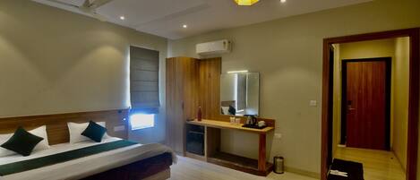 A hotel room with a bed, bedside table, mirror, and a door leading to another room.