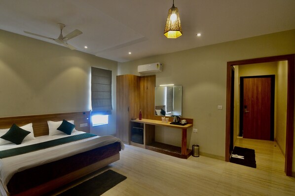 Una habitación de hotel con cama, mesita de noche, espejo y puerta que da a otra habitación.