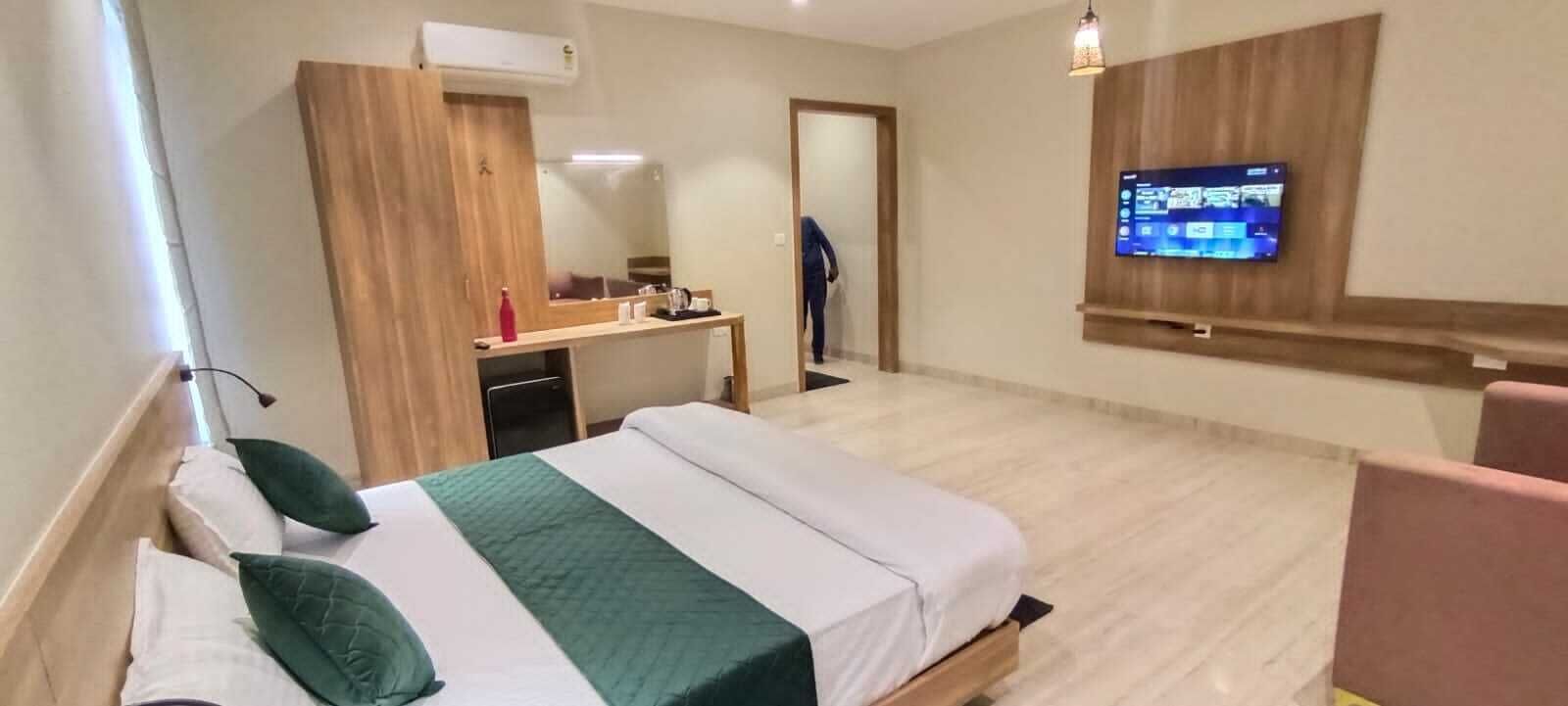 A hotel room with a bed, a desk, a TV, and a wardrobe.