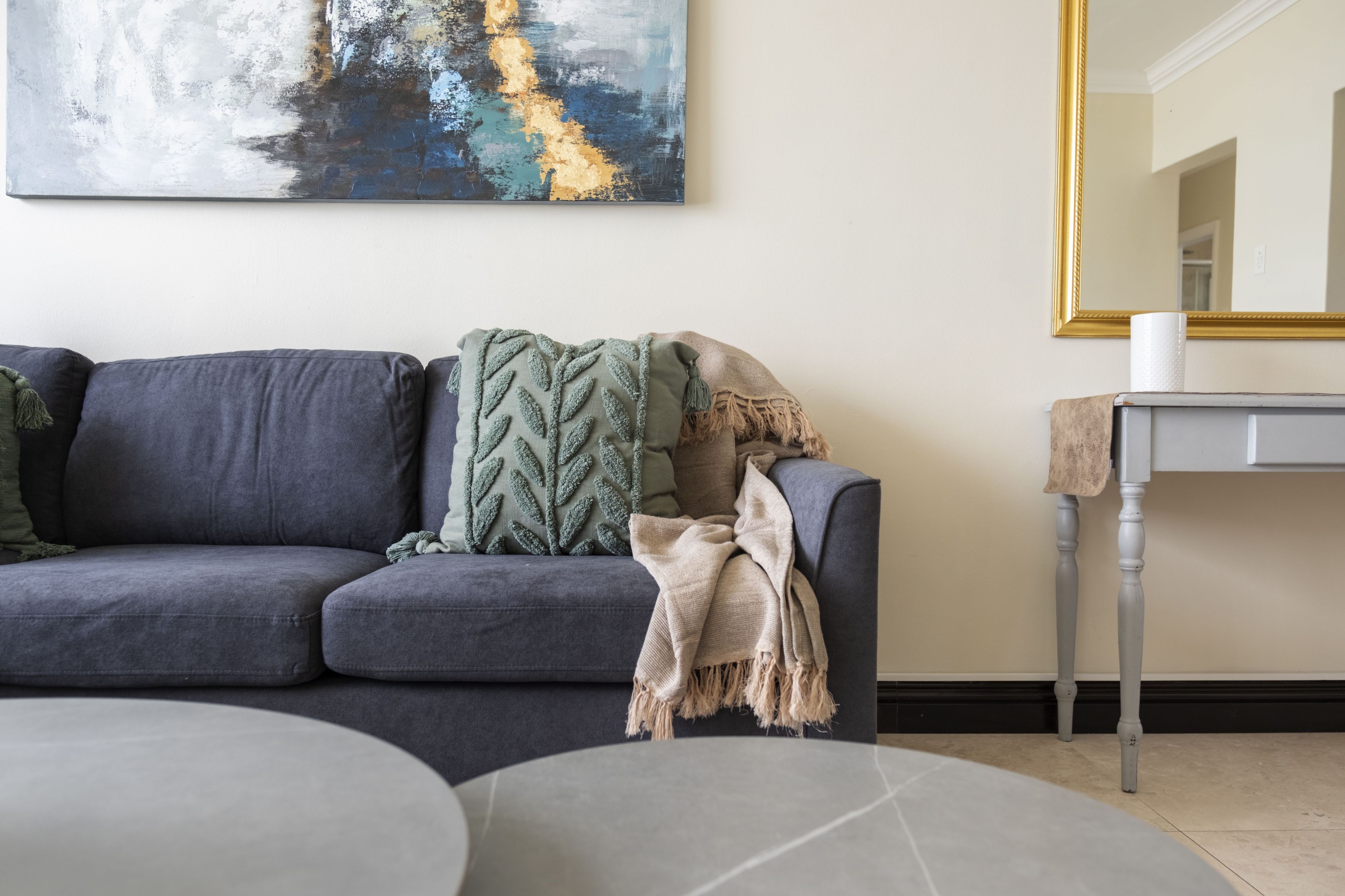 A living room with a gray sofa, a round coffee table, and a painting on the wall.