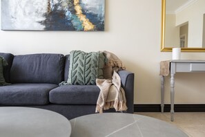 A living room with a gray sofa, a round coffee table, and a painting on the wall.