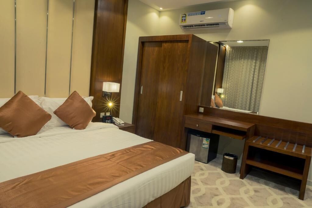 Ein Hotelzimmer mit Bett, Schreibtisch, Spiegel und Klimaanlage.