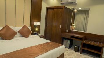 Ein Hotelzimmer mit Bett, Schreibtisch, Spiegel und Klimaanlage.