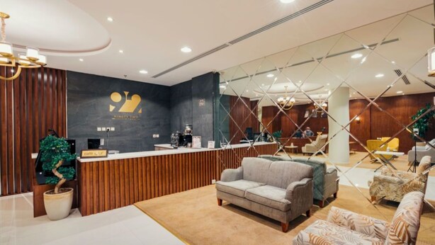 A modern hotel lobby with a reception desk, sofas, and a decorative plant. - Ninety Two (Unaizah)