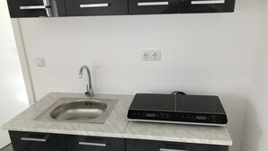 Una cocina con pileta integrada, muebles de color negro y una cocina por inducción negra.