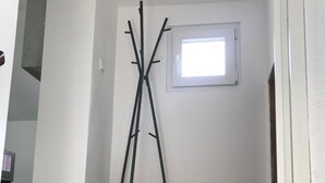 Una habitación con piso de madera, una ventana con persianas y un perchero.