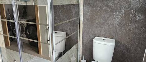 Een moderne badkamer met een douchecabine van glas, een toilet en een bidet.