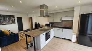 Una cocina moderna con armarios blancos, un refrigerador negro y una isla central con asientos.