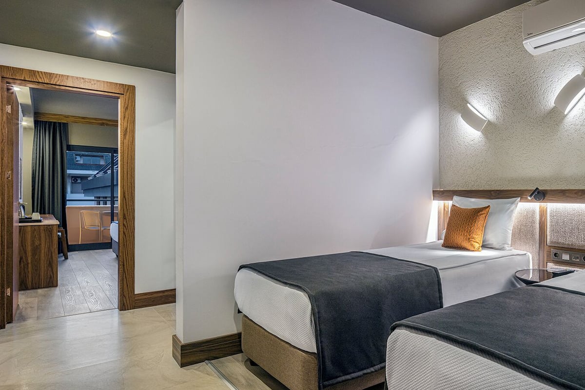 A hotel room with two beds, a wooden desk, and a view of the outside.