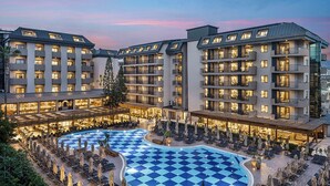 A hotel with multiple floors, a central courtyard pool, and outdoor seating areas. - Kaia Coracesium (Alanya)