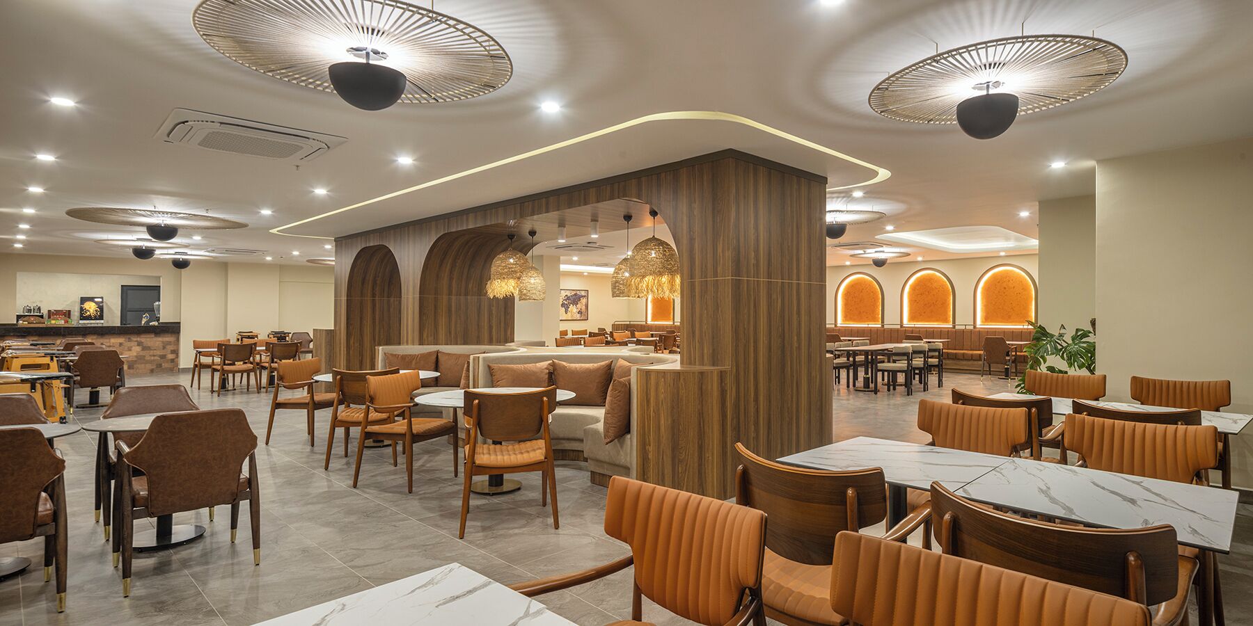 Un restaurante moderno con mesas redondas, asientos acolchados e iluminación de techo original.