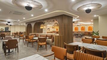 Un restaurante moderno con mesas redondas, asientos acolchados e iluminación de techo original.