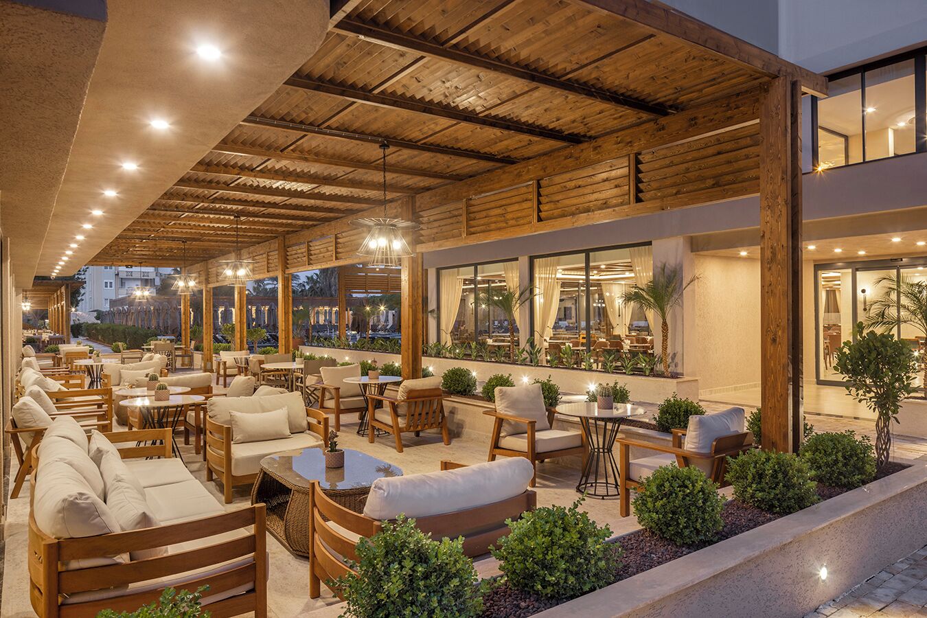 Un espacio al aire libre con mobiliario de madera y vista a la ciudad al anochecer.