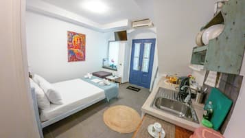 Habitación de hotel pequeña con cama, un escritorio, un lavabo y un cuadro de colores en la pared.