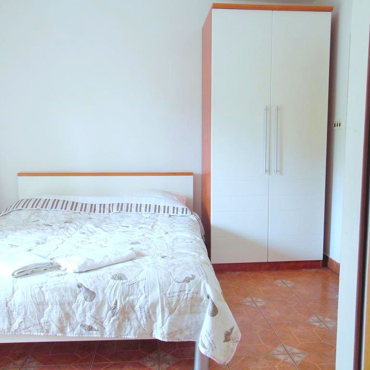 Une chambre à coucher avec un lit, une armoire et un sol carrelé.