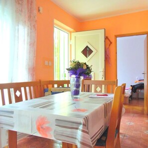 Zona pranzo con tavolo, sedie e un vaso con fiori.