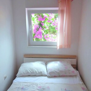 A bedroom with a window, a bed with white bedding, and a wooden headboard. - Floral Apartments Yazzy 1 (Novalja)