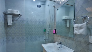 A modern bathroom with a glass-enclosed shower, a white sink, and a mirror. - Clay Inn Hotel Gurugram (Gurugram)