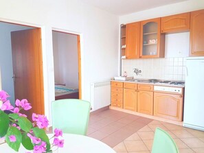 A compact kitchen with wooden cabinets, a gas stove, and a white dishwasher. - Floral Apartments Yazzy 2 (Novalja)