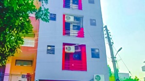 A multi-story building with a flat facade, air conditioning units, and a motorcycle parked in front. - Roomshala 155 Hotel JPC (New Delhi)