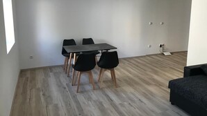 Een moderne kamer met een eettafel en stoelen, een bank en een houten vloer.