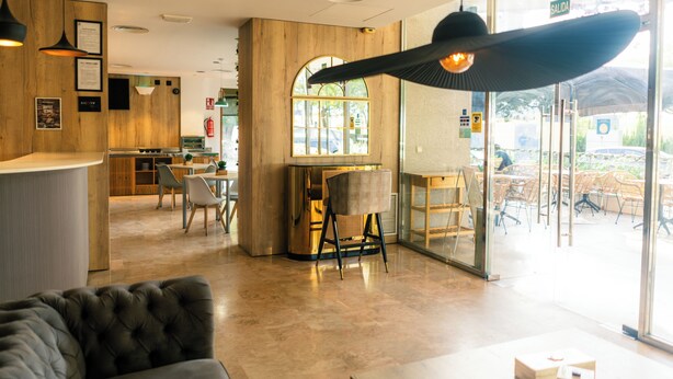 Un intérieur moderne comprenant un comptoir d’accueil, un espace détente et de grandes fenêtres.