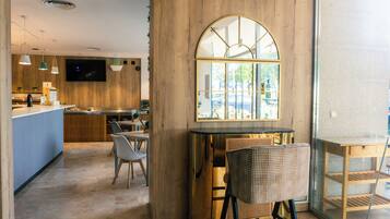 Un interior de restaurante moderno con una pared de acento de madera, un gran ventanal arqueado y una zona de bar.