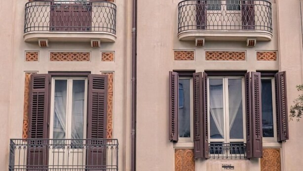 Un bâtiment doté de fenêtres à deux étages, chacune étant agrémentée d’un balcon orné de balustrades en fer forgé.