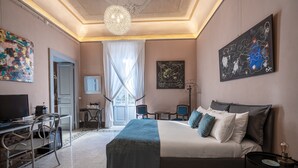Une chambre d’hôtel équipée d’un lit, d’un bureau, d’une chaise, d’une télévision et d’œuvres d’art.