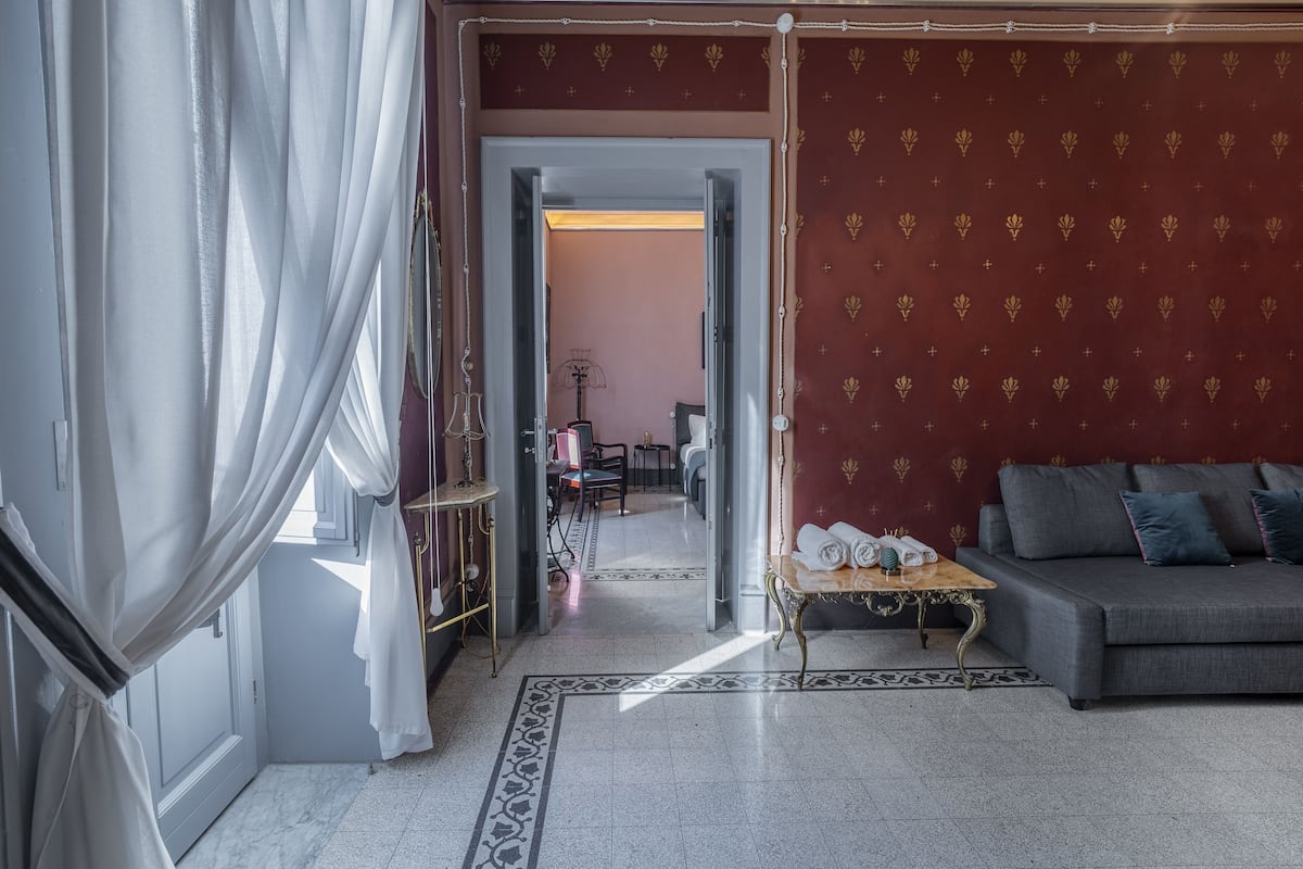 Habitación con sofá, una mesita de centro y pared con estampado. Se ve una puerta que da a otra habitación.