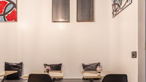 Une galerie d’art contemporain au design minimaliste, avec un plancher en bois, des chaises noires et des peintures abstraites.
