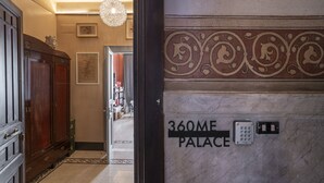 Un mur de marbre portant l’inscription « 360ME PALACE » et muni d’un clavier, indiquant l’entrée d’un hôtel ou d’un immeuble.