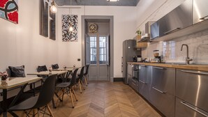Une cuisine moderne dotée d’appareils électroménagers en acier inoxydable, d’un parquet en bois disposé en chevrons et d’un coin repas avec des chaises noires et une table en verre.