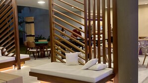 A modern hotel room with a wooden partition, a sofa bed with white cushions, and a dining area with chairs and a table. - Makia Beach Resort Experience By All (Ipojuca)